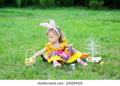 Adorable toddler girl wearing bunny ears playing with Easter eggs  sitting in a sunny garden  - Shutterstock ID 243359425