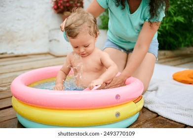 Adorable toddler playing in a multicolored inflatable pool with the attentive care of a mother. A delightful moment of summer fun and bonding. - Powered by Shutterstock