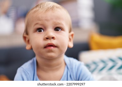 Adorable Toddler Sitting On Sofa With Relaxed Expression At Home