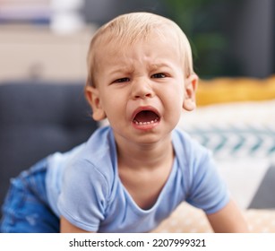 Adorable Toddler Sitting On Sofa Crying At Home