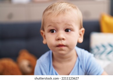 Adorable Toddler Sitting On Sofa With Relaxed Expression At Home