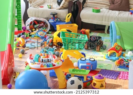 Adorable toddlers playing among the many toys at home. A mess in the children's room, a lot of toys in the children's room. Dirty house. Children's room. Selective focus 