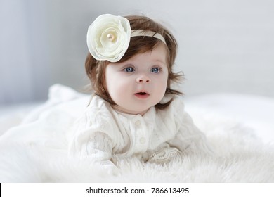 Adorable two month old baby girl lying on the pillow and looking into the camera. Portrait of a little baby on a soft blanket