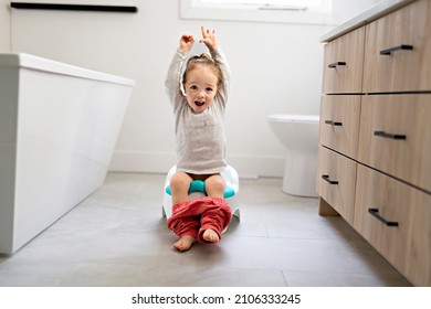 An Adorable young baby child sitting and learning how to use the toilet