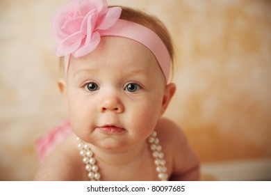 Adorable Young Baby Girl Wearing A Vintage Pearl Necklace And Pink Rose Headband