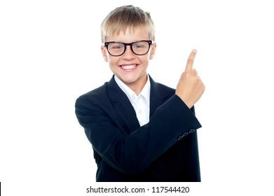 An adorable young boy in formals pointing towards copy space area