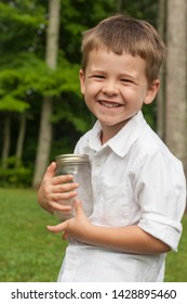 Adorable Young Boy Smiling And Holding A Jar With Fireflies Or Lightning Bugs In It. 