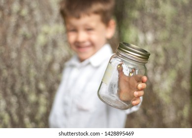 Adorable Young Boy Smiling And Holding A Jar With Fireflies Or Lightning Bugs In It. 