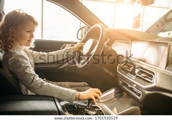 adorable young caucasian child girl want
parents to buy this car, she sit at the wheel of new auto, girl
likes it. in
dealership