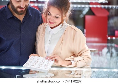 Adorable Young Couple Smiling While Choosing Rings For Wedding At The Local Jewelry Store.