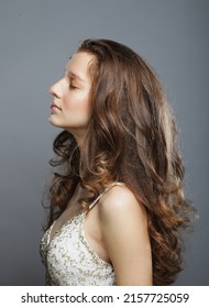 Adorable young female model with long curly hair in white dress posing in profile, purity and innocence - Shutterstock ID 2157725059
