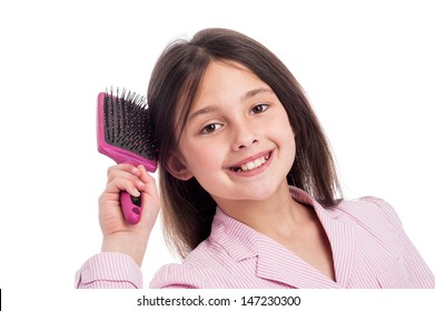 Adorable young girl looking to camera while she brushed her hair. Isolated on white studio background.