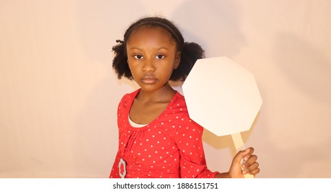 Adorable Young Girl With Serious Face Wearing Red Holding Up Blank White Octagon Sign Indoors White Background 