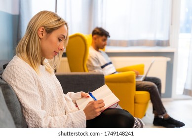 Adorable young girl writing at a book while boyfriend work at th