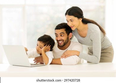 Adorable Young Indian Family Using Laptop At Home