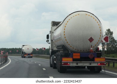 ADR hazardous goods transportation on road. White semi trucks liquid gas tanker with copy space place blank on barrel drive on asphalt motorway at summer day, Back view.  - Shutterstock ID 2232415437
