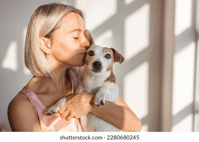 Adult 40s woman with her cute dog Jack Russell Terrier in armchair at home. Lovely pet