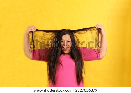 Adult 40-year-old Latina woman ruffles her hair desperate with anxiety and frustration with very long straight damaged hair