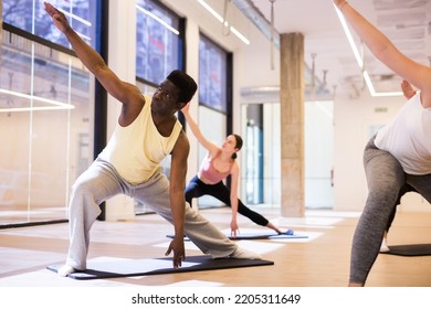 Adult African American Maintaining Active Lifestyle Exercising During Group Pilates Class In Modern Fitness Center