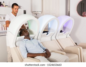 Adult African American Man Leaning Heads On Sink And Relaxing 
While Hairdresser Washing His Hair In Barbershop