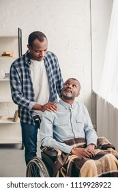 adult african american son looking at disabled senior father in wheelchair
