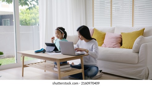 Adult asia people single mom small SME owner support happy sit busy apply child tax credit refund plan form app or pay loan bill on laptop. Little kid girl play at home hybrid job career workforce. - Powered by Shutterstock