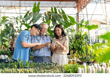 Adult Asian couple with elderly man father walking and choosing plant at plant shop street market on summer vacation. Family relationship, fathers day and senior people mental health care concept.