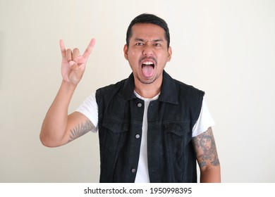 Adult Asian Man Doing Rockstar Pose. Sticking Tongue Out  