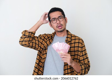 Adult Asian Man Holding Paper Money And Showing Confused Face Expression