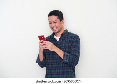 Adult Asian Man Leaning On The Wall While Using Mobile Phone With Happy Face