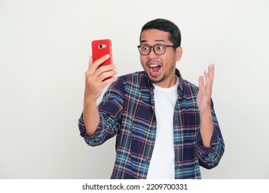 Adult Asian man looking to his mobile phone with wow expression