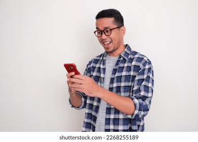 Adult Asian man looking to his mobile phone with happy expression - Powered by Shutterstock