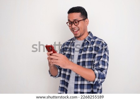 Adult Asian man looking to his mobile phone with happy expression
