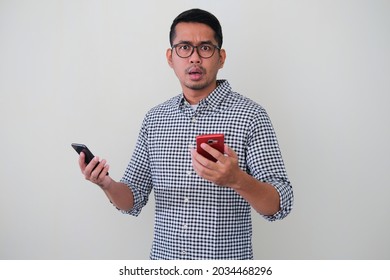 Adult Asian Man Showing Confused Face Expression While Holding Two Mobile Phone