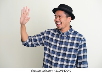 Adult Asian Man Showing Excited Expression When Waving Hand To Greet Someone