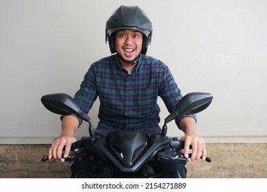 Hombre asiático adulto mostrando expresión de entusiasmo cuando conduce una motocicleta