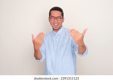 Adult Asian man showing excited expression while doing inviting hand gesture - Powered by Shutterstock