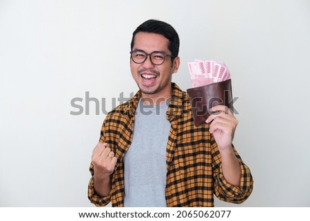 Adult Asian man showing excited face expression while holding his wallet full of money