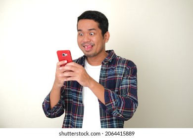 Adult Asian Man Showing Funny Excited Face Expression When Typing On Mobile Phone