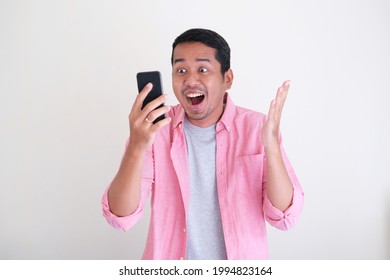 Adult Asian Man Showing Happy Face Expression While Looking To The Mobile Phone Screen