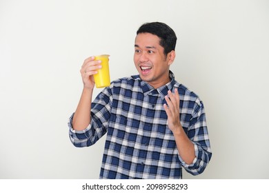 Adult Asian Man Showing Happy Face When Looking To A Cup Of Cold Yellow Fruit Juice Drink