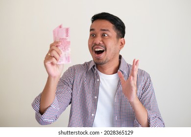 Adult Asian Man Showing Shocked Face Expression While Looking To Paper Money That He Grab