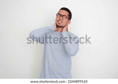 Adult Asian man suffering pain in back of his neck