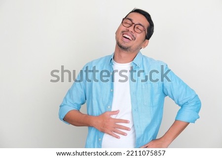 Adult Asian man touching his belly with relieved expression