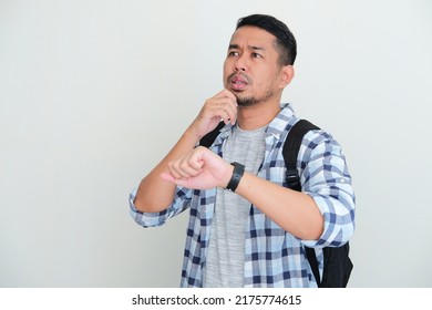 Adult Asian Man Wearing Backpack Waiting For Someone To Pick Him Up With Unsure Expression