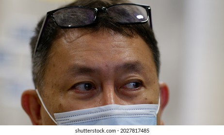 Adult Asian Man Wearing Medical Mask   With Glasses Over Head. Close Up Of Asian Man In Blue Medical Face Mask. Jakarta. 2021.