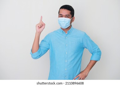 Adult Asian Man Wearing Medical Mask Showing Happy Expression While Pointing Finger Up