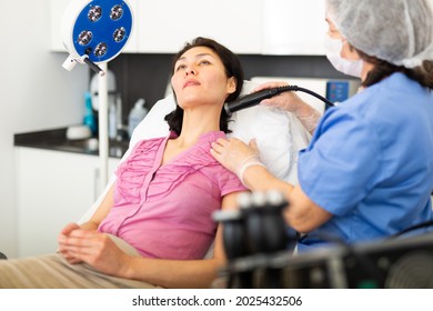 Adult Asian Woman Receiving Facial Electroporation Procedure From Experienced Cosmetologist In Aesthetic Medicine Office