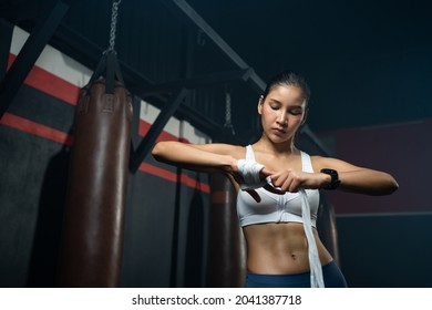 Adult Asian women using elastic bandage to tie on her hands before put on a boxing glove for boxer training class, Sport, fitness and exercise concept for good health and strong muscle and body. - Powered by Shutterstock