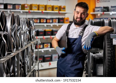 adult auto mechanic man in uniform have rest after hard working day, standing by rack of car wheels. auto, car, transport concept - Shutterstock ID 1917532154